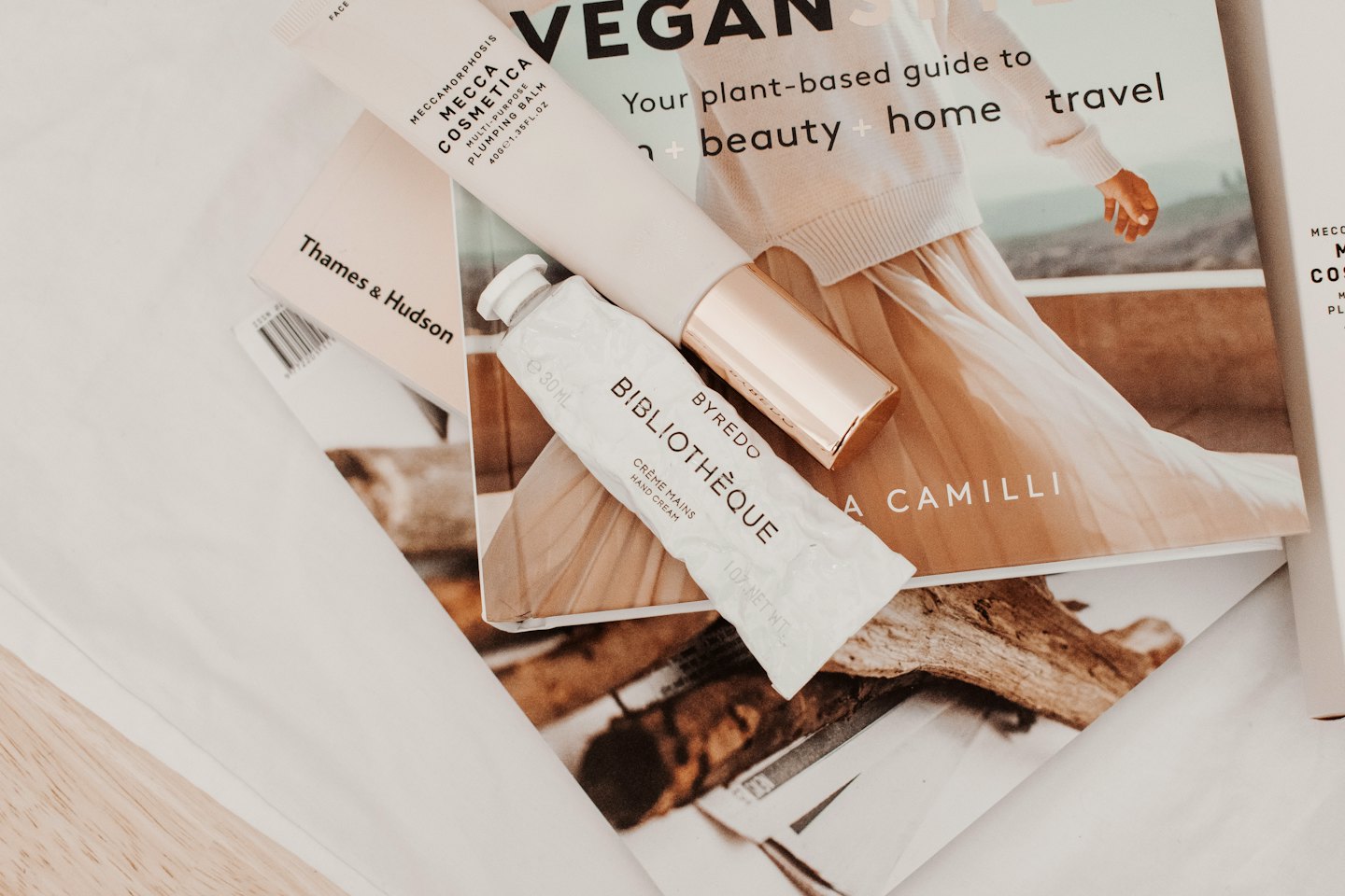 Beauty products and a book arranged on a white surface.